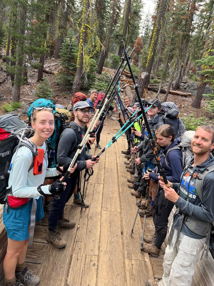 a group of hikers holding up their hiking poles to make a bridge