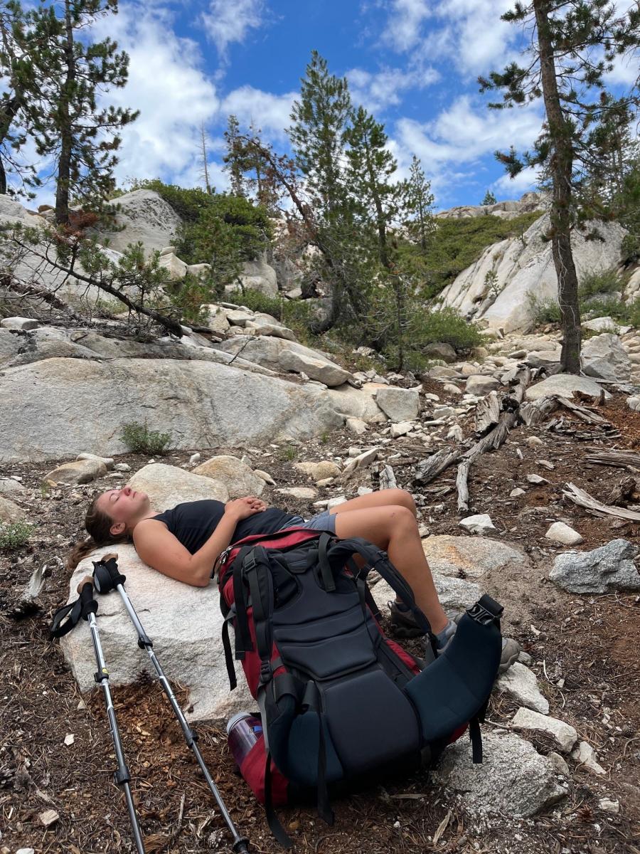 a woman resting on a rock outdoors